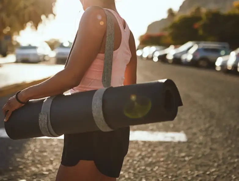 Woman walking through parking lot with yoga mat, promotional image to represent multi day pass parking options through Secure Parking USA